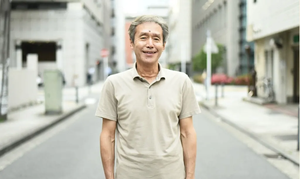 街並みを背に立つ田川尚登さん