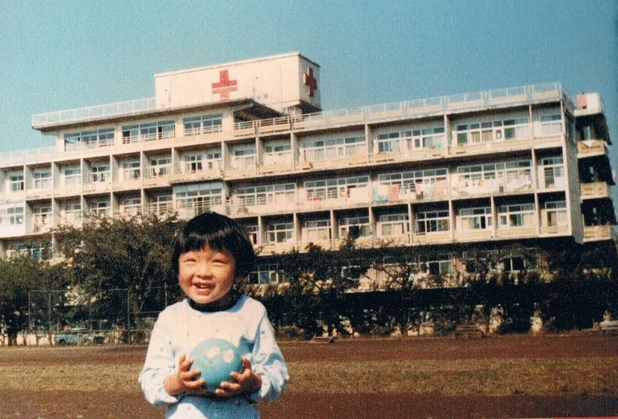 幼少期、病院の前でボールを手に笑うなかはちさん