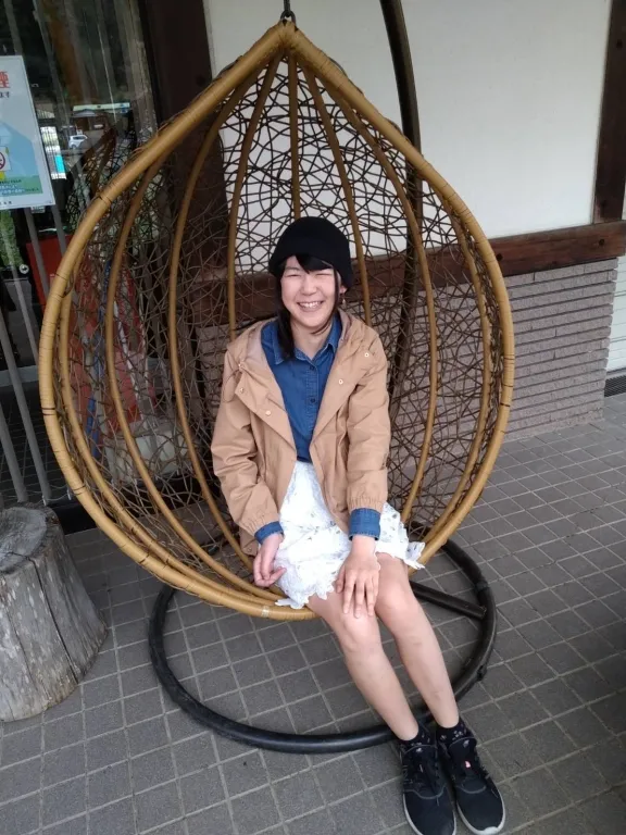 ハンギングチェアに座って微笑む春香さん