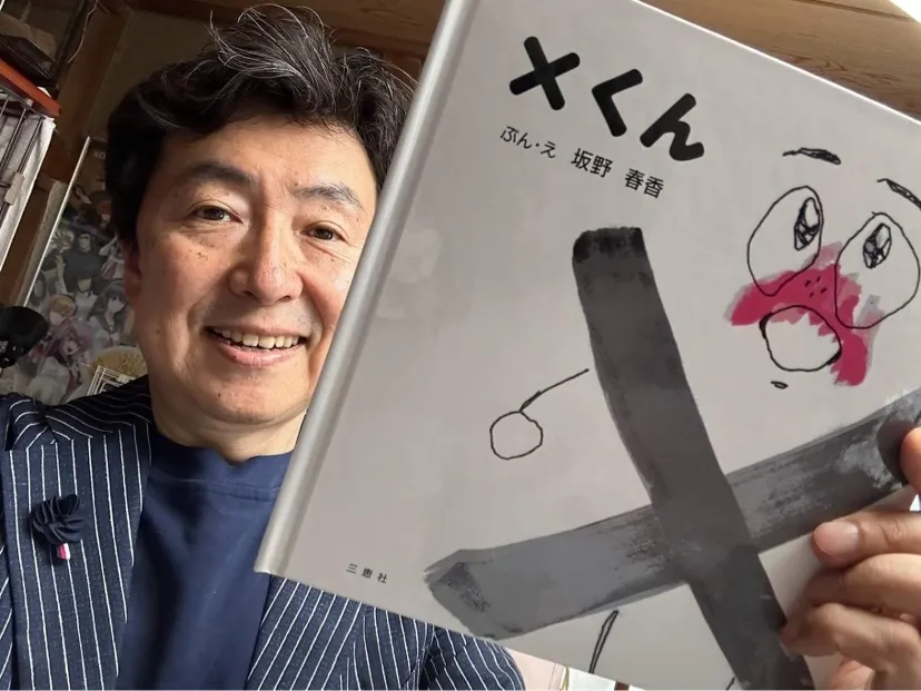 絵本「X（バツ）くん」を手に微笑むお父様の坂野貴宏さん